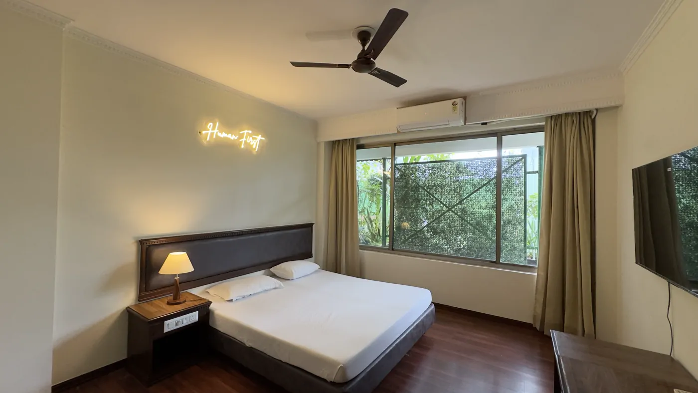 Private room with a Human First neon sign and a garden-facing window